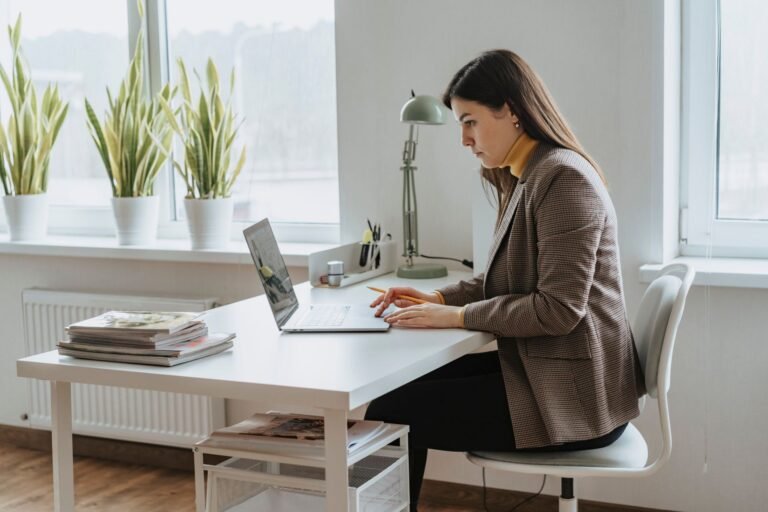 A professional woman sits at a desk in front of her laptop during a virtual interview.
