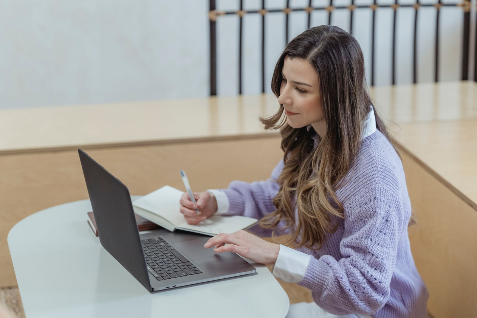 Professional woman planning her job search while using a laptop and taking notes.